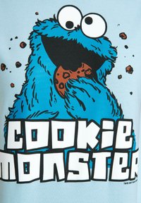 Blue t-shirt featuring a graphic of Cookie Monster eating a cookie. Text reads "COOKIE MONSTER" in bold black letters. Soft cotton material.