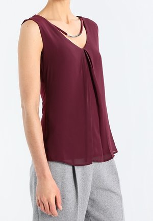 Top burdeos sin mangas con escote en V, con un detalle plateado y diseño drapeado. Hecho de tela ligera y translúcida.