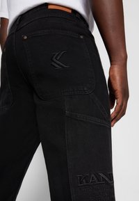 Karl Kani RETRO SLIT PANTS - Calças de ganga de perna direita - black