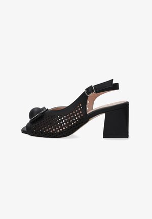 Schwarzer Slingback-Schuh mit offener Zehenpartie und Blockabsatz, der ein ausgeschnittenes Gitterdesign sowie einen runden Akzent an der Vorderseite aufweist. Flache Schnallenverschluss.