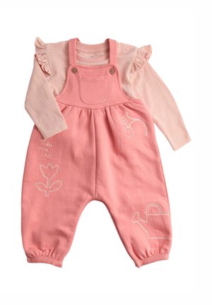 Różowy bawełniany kombinezon z falbaniastą bluzką w paski z długim rękawem pod spodem. Posiada haftowane kwiaty, konewkę i przednią kieszeń.