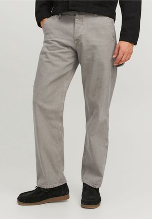Pantalons décontractés gris clair en mélange de coton, présentant une coupe droite, une texture subtile et des poches latérales. Associés à des chaussures noires.
