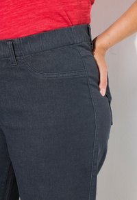 Pantalones de mezclilla gris oscuro con un diseño ajustado, que cuentan con bolsillos laterales y una textura suave. La cinturilla es elástica y se ajusta en la cintura natural.