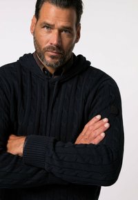 Felpa navy a maglia cable-knit con tasca a marsupio, polsini a coste e un design testurizzato. Presenta un logo ricamato sulla manica sinistra.