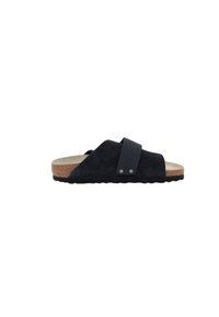 Black suede slide sandal with a cork sole, featuring a textured strap and two metal accents, providing a casual and comfortable design.