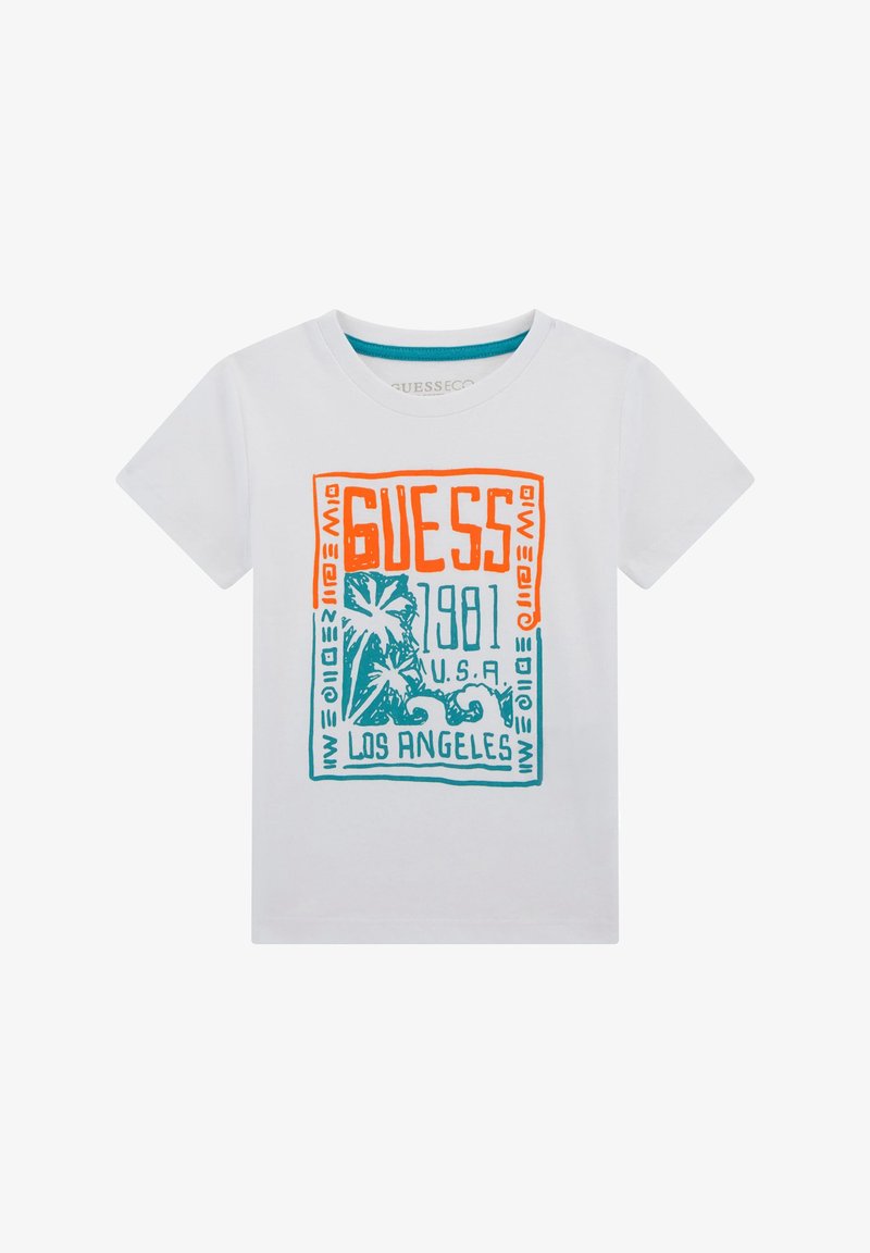 T-shirt in cotone bianco con una stampa grafica colorata che presenta "GUESS," palme e "1981," in arancione e turchese. Maniche corte e colletto tondo.