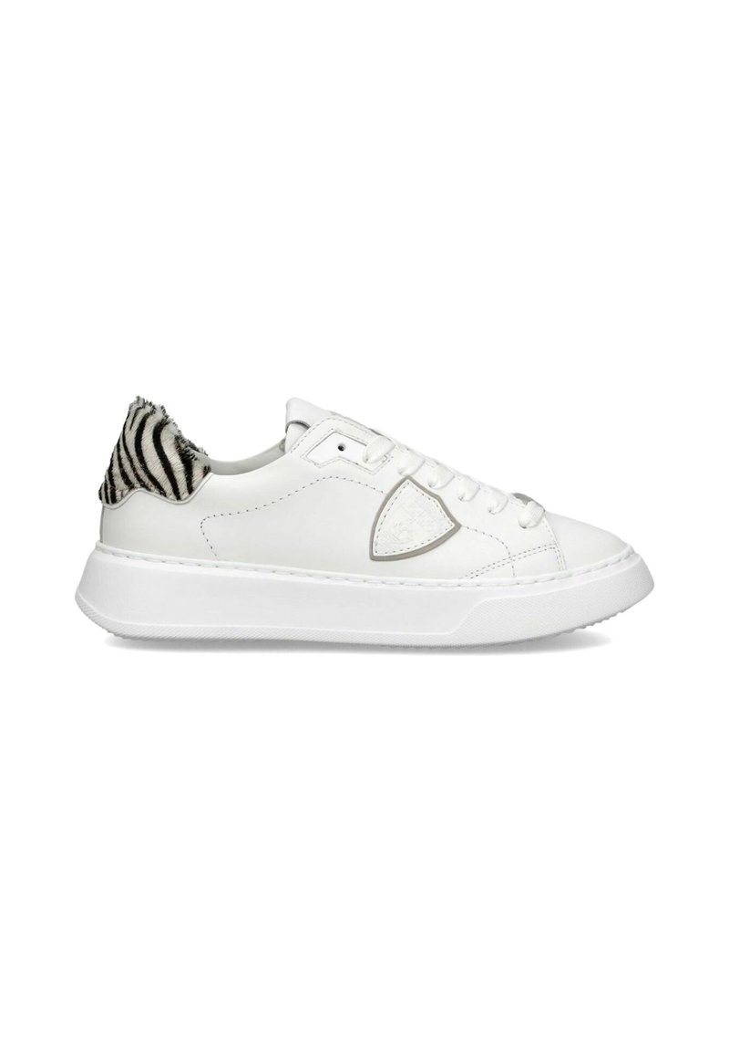 Hvide lædersneakers med et struktureret sort og hvidt stribet materiale ved hælen. Har en afrundet tå og flad gummisål.