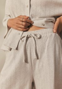 Lichtgrijze gebreide loungewear set met een knoopsluiting bovenstuk en broek met aantrekkoord, voorzien van een gemêleerd patroon en ontspannen pasvorm.