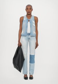 Denimvest, kus on kulunud detailid, koos helesiniste lapitöödega teksadega, hoides musta nahkse kotti. Lame mustad jalanõud lõpetavad välimuse.