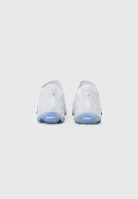 White athletic shoes with a textured surface, featuring a small silver logo, padded collar, and a blue accent on the rubber sole.