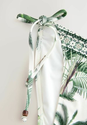 Grön och vit bikinitopp med palmbladsprint, med knytning och dekorativa pärlor. Mjuk tyg med en slät textur och elastisk design.