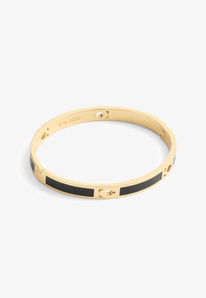 Bracciale in metallo dorato con dettagli in smalto nero e ritagli, con il marchio Coach inciso sulla parte interna.