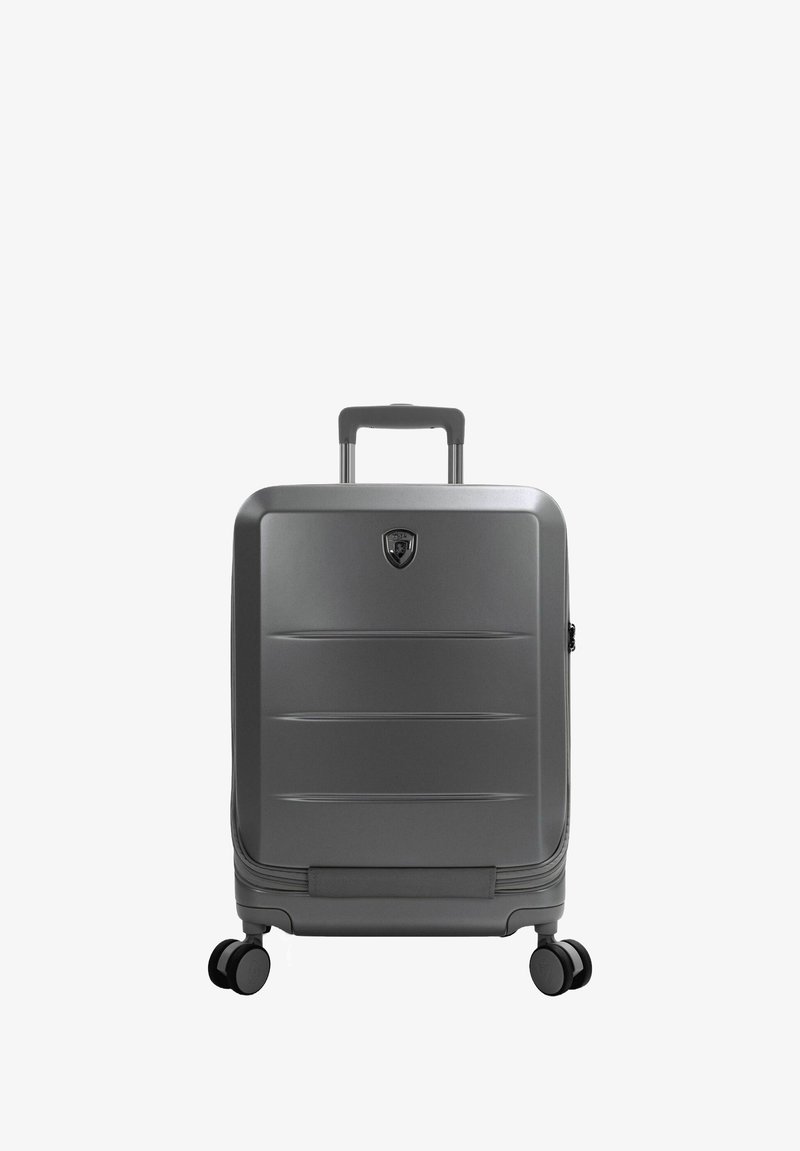 Grijze harde koffer met horizontale groeven, een telescopische handgreep en 360-graden draaibare wielen. Voorzien van een logo aan de voorkant.