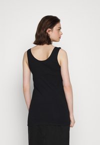 Top preto de alças largas com decote redondo, feito de tecido macio e elástico, apresenta corte ajustado até à cintura.