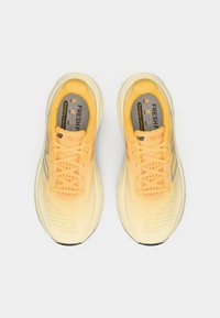 Par žutih New Balance tenisica za trčanje s vezicama, pjenastim potplatima i vidljivom oznakom "Fresh Foam" unutra.