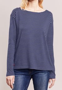 Marineblaues langärmliges Oberteil mit weißen horizontalen Streifen, aus weichem Stoff. Verfügt über einen Bootsausschnitt und leicht fallende Schultern.