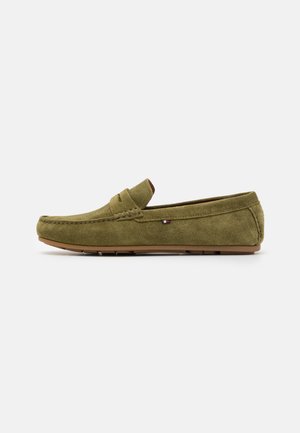 Olivgrüne Wildleder-Lockschuhe im Mokassin-Stil mit dekorativen Nähten und einem dezenten Logo an der Seite. Gummisohle.