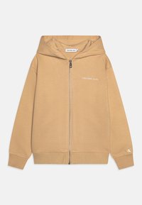 Sudadera con capucha y cremallera en color beige, confeccionada con tela suave. Cuenta con capucha, puños acanalados y logo bordado de "Calvin Klein Jeans" en el pecho.