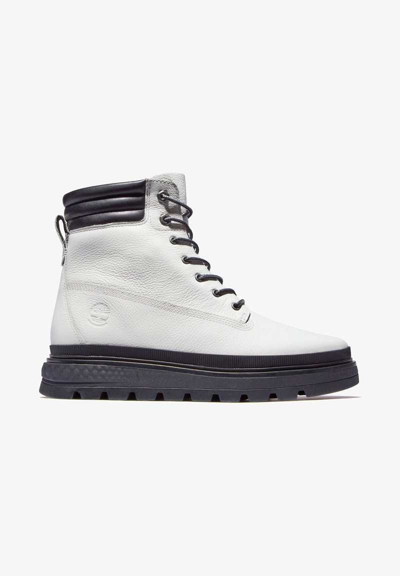 Bottine blanche en cuir avec col matelassé noir, lacets noirs, semelle noire épaisse à crampons et logo embossé sur le côté.