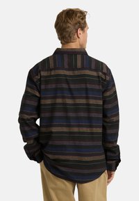 Gestreept shirt in zwarte, blauwe en bruine tinten. Heeft lange mouwen, een klassieke kraag en een ontspannen pasvorm met een afgeronde zoom.