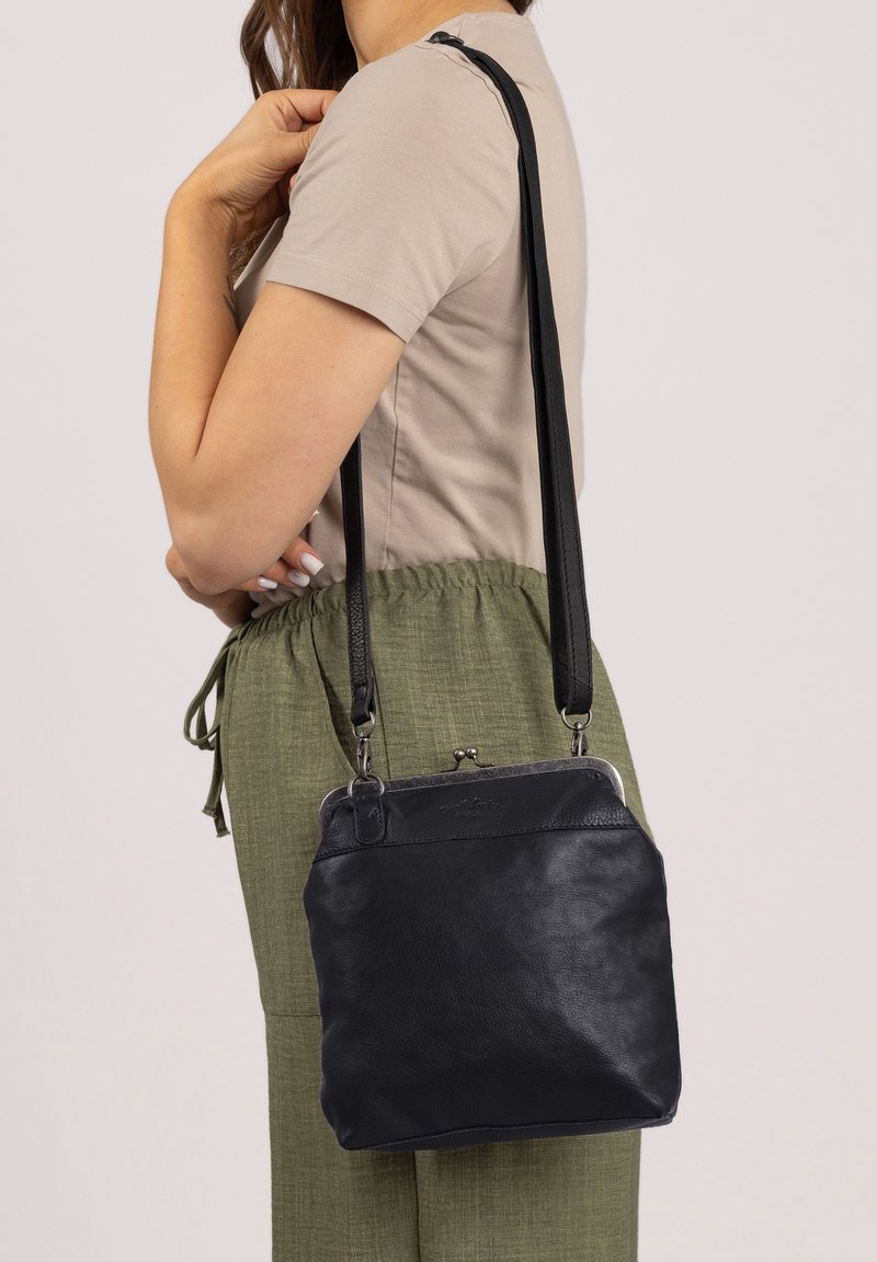 Black leather crossbody bag with a structured design, silver hardware, and a clasp closure. Features adjustable straps and a smooth texture.