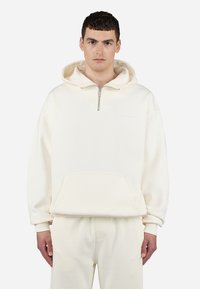 Lyse beige sweatshirt med halv-zip design, frontlomme og ribbede manchetter. Blødt stof med et minimalistisk logo på brystet. Sæt med matchende bukser.