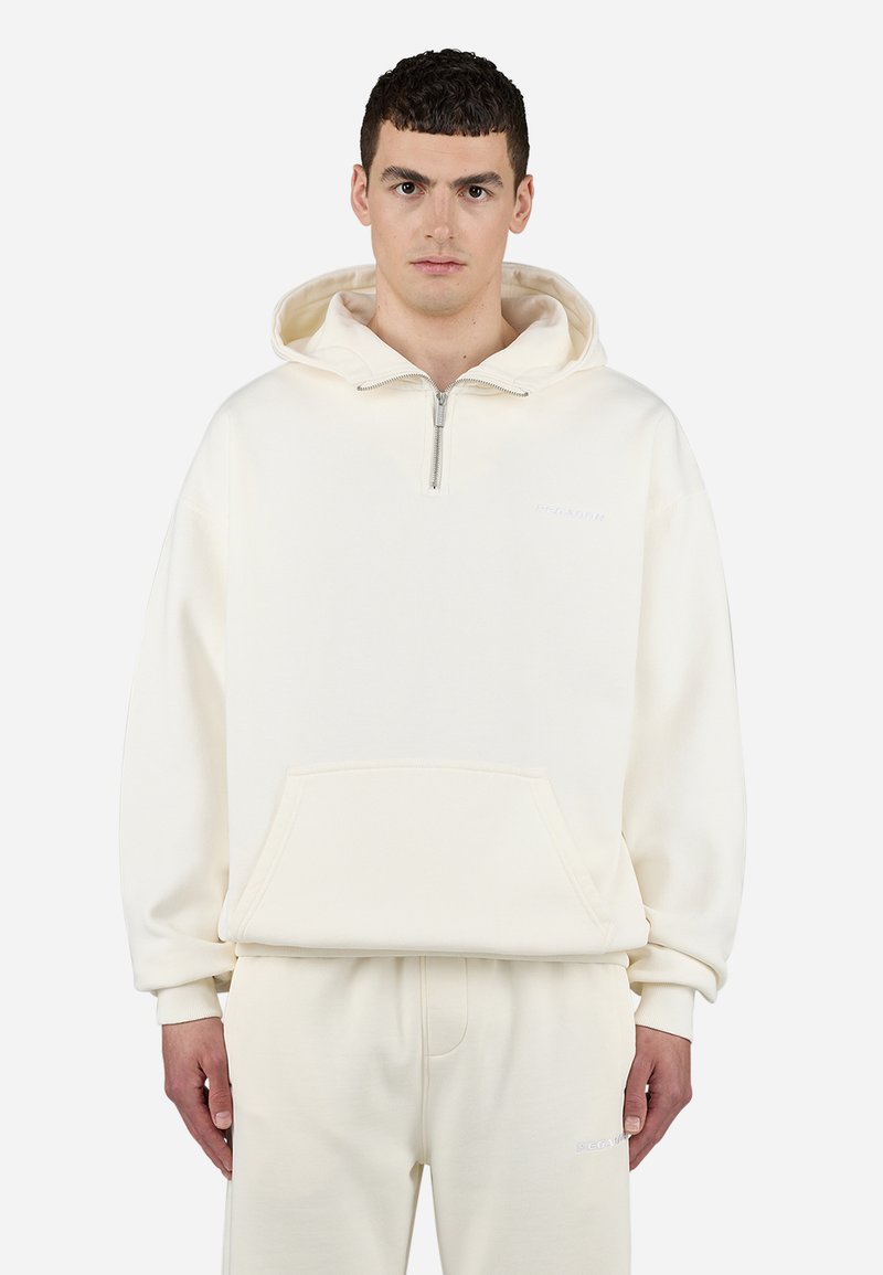 Lyse beige sweatshirt med halv-zip design, frontlomme og ribbede manchetter. Blødt stof med et minimalistisk logo på brystet. Sæt med matchende bukser.