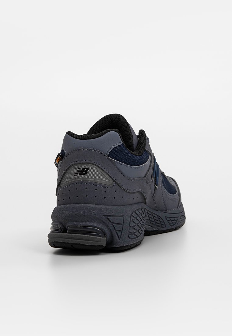 Marineblaue und graue Sportschuhe mit einer strukturierten Oberschicht, gepolsteter Sohle und schwarzen Akzenten. Verfügt über ein Mesh-Innenfutter und ein gemustertes Profil.