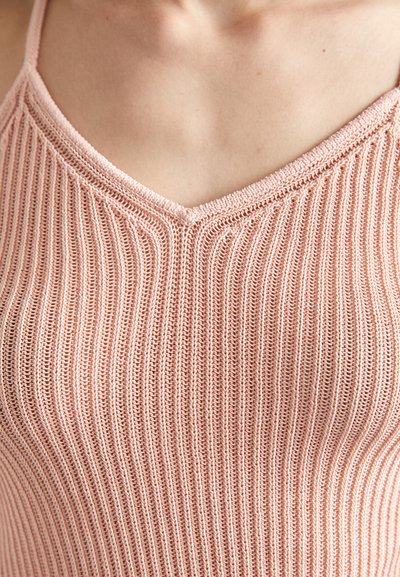 Vaaleanpunainen neulottu tanktoppi, jossa on V-mallinen kaula-aukko, pystysuora ribbineulos ja ohuet hihnat. Kangas vaikuttaa kevyeltä ja hengittävältä.