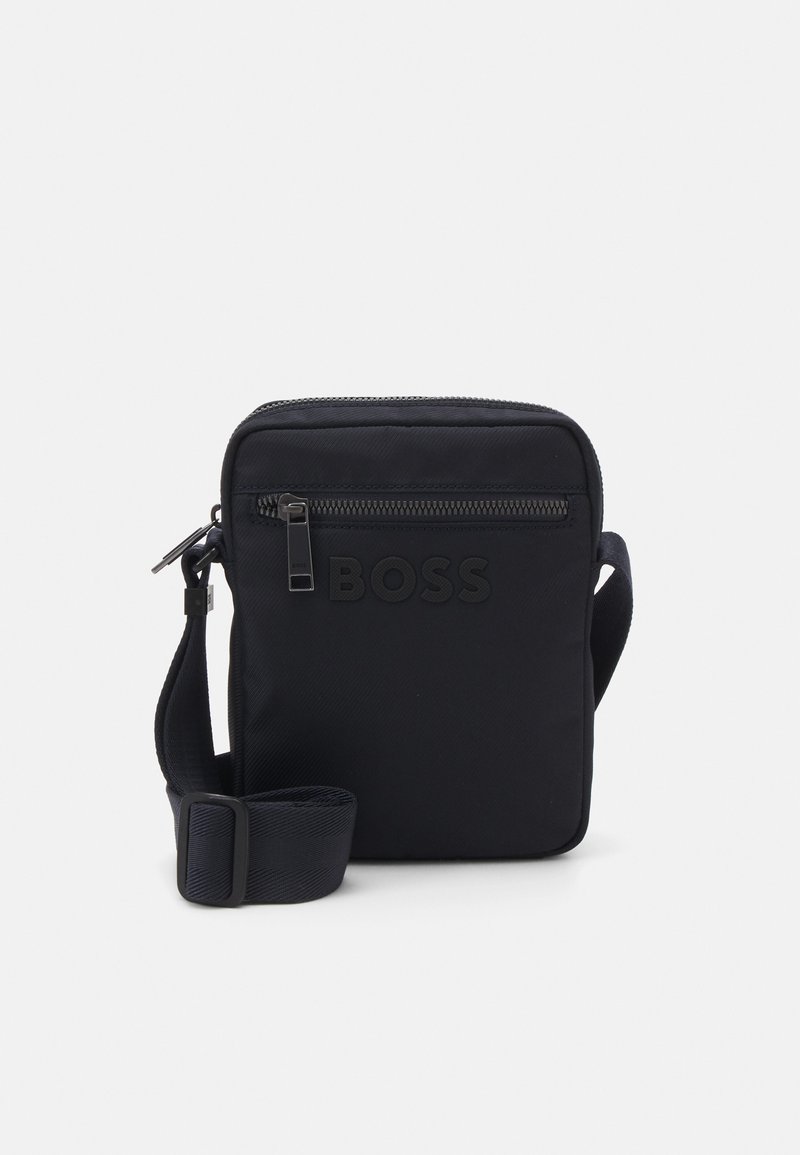 Borsa a tracolla nera in nylon texturizzato, dotata di una tasca frontale con zip e di una tracolla regolabile. Logo embossato sulla parte anteriore.