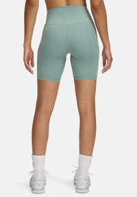 Shorts de vélo high-waisted vert menthe en tissu lisse et extensible; dotés de poches latérales et de coutures plates pour le confort et le soutien.