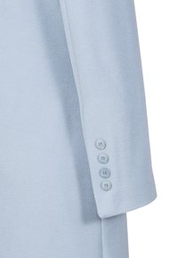 Lichtblauwe blazer van textuurstof. Voorzien van een reverskraag en vijf bijpassende knopen op de manchetten, wat een tailormade ontwerp benadrukt.