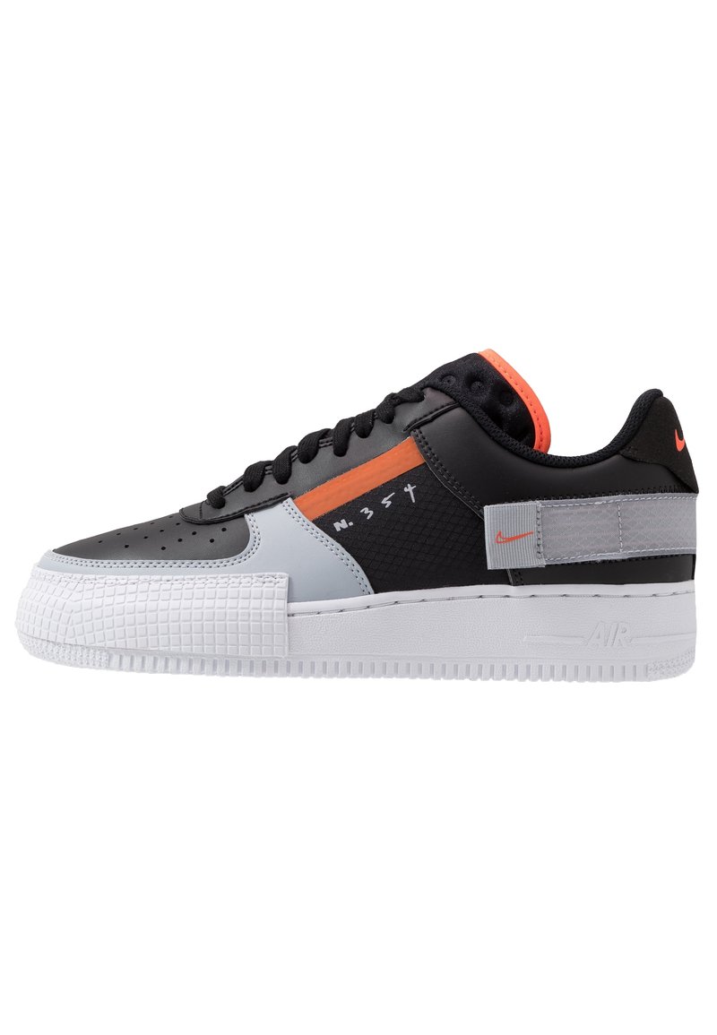 Svart, vit och grå sneakers med en texturerad mellansula, orange accent, perforerad tå och logodetaljer. Har en platt snörningsdesign.