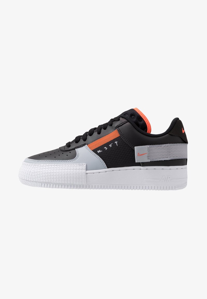 Svart, vit och grå sneakers med en texturerad mellansula, orange accent, perforerad tå och logodetaljer. Har en platt snörningsdesign.