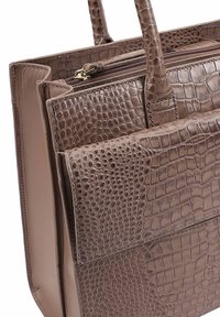 Lichtebruine faux leren handtas met krokodillenpatroon, voorzien van dubbele handvatten en een ritssluiting, gekenmerkt door textuurelementen en strakke lijnen.