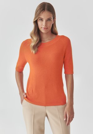Orange ribbed knit sweater with short sleeves and a round neckline, paired with light beige trousers. Smooth texture and fitted design.