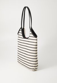 Sac fourre-tout rayé crème et noir. Fabriqué en matériau tissé avec des poignées noires lisses. Présente un détail de chaîne et de breloque sur un côté.