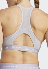 Lichtgrijze sportbh met een racerback ontwerp, gaasdetails en een brede elastische band met het label "TECHFIT." Gladde textuur en nauwsluitende pasvorm.