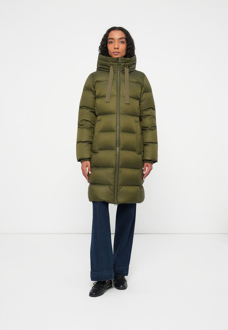 Chaqueta de plumas de color verde oliva, con un alto cuello, cremallera frontal y grandes bafles horizontales. Equipado con cordones y puños acanalados.