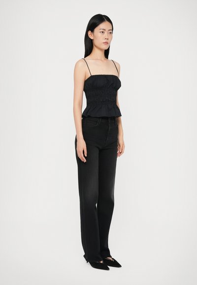Čierny peplum top s nastaviteľnými špagetovými ramienkami a zhromaždenými detailami, držiaci sa s vysokými čiernymi rovnobežnými džínsy a špicatými balerínami.