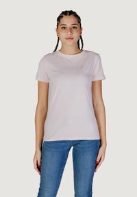 Lichtroze katoenen t-shirt met korte mouwen en ronde hals. Heeft een subtiel verhoogd "GUESS" logo op de borst. Getailleerd ontwerp.