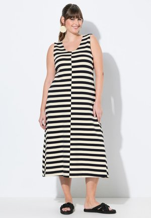 Robe maxi rayée noire et beige avec un décolleté arrondi, sans manches et coupe décontractée, associée à des sandales à glissière noires nouées.