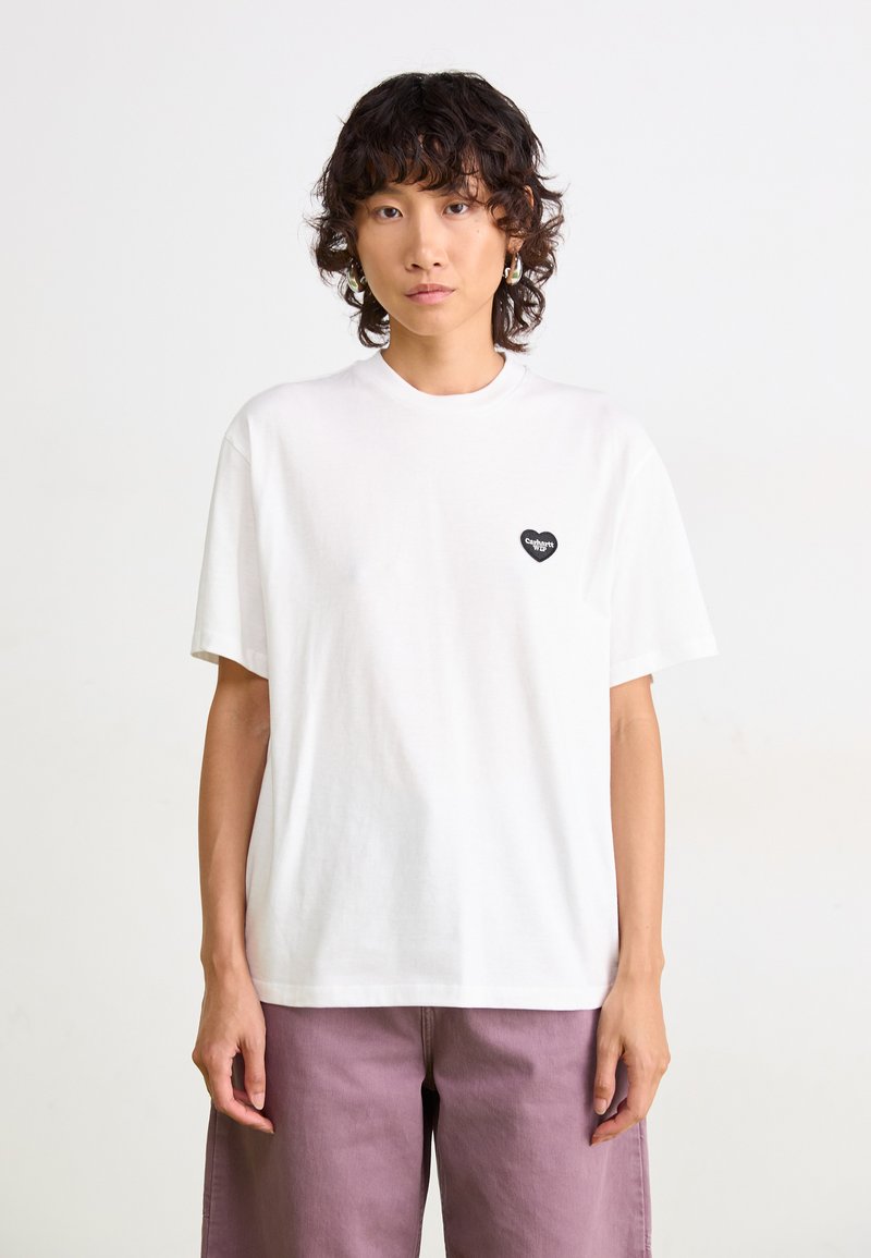 White cotton t-shirt with short sleeves, features a small black heart logo on the left chest. Simple, relaxed fit design.