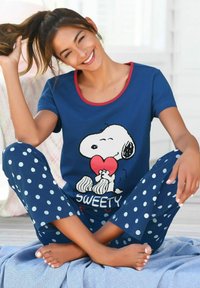 Marineblaue Schlafanzugset mit weißen Punkten, versehen mit einem Snoopy-Motiv, der ein Herz hält. Weicher Stoff, kurze Ärmel und runder Halsausschnitt.