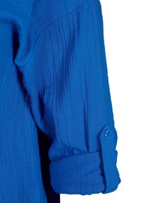 Blue, textured shirt fabric with a rolled cuff and a button accent. Wrinkled design adds depth to the overall appearance.