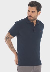 Polo shirt blu navy in cotone, con colletto, maniche corte e logo ricamato sul petto. Dettagli arancioni.