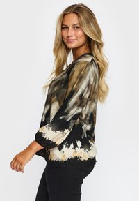 Silke sort og beige tie-dye bluse med trekvart pufærmer og en rund halsudskæring, der har et lyst abstrakt mønster.