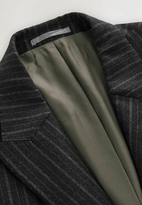 Donkergrijze colbert met een lichte textuur, voorzien van een gladde olijfgroene satijnen voering en een gesneden kraag.