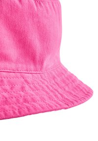 Chapeau seau rose vif en tissu doux, avec un large bord plat et une texture cousue le long du bord et de la calotte.