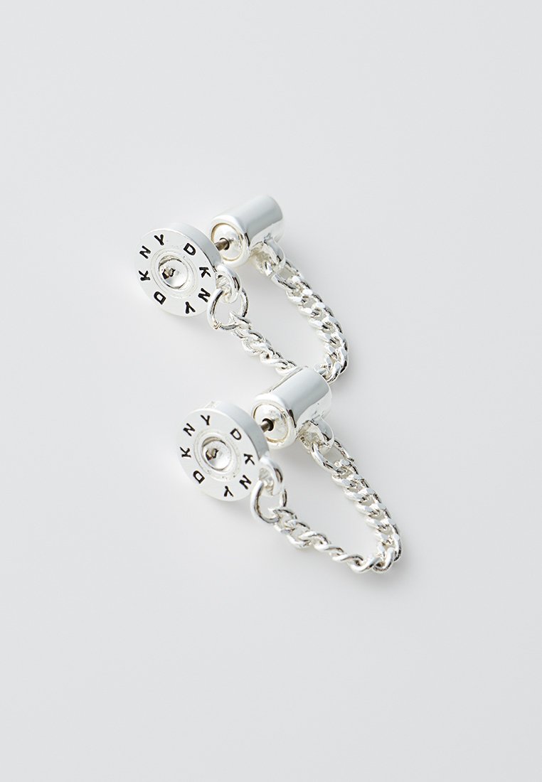 Srebrne kolczyki łańcuszkowe z okrągłymi akcentami z wyciętymi literami. Gładka powierzchnia metalu z polerowanym wykończeniem i skręconym wzorem.